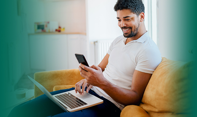 Man looking  at mobile phone and laptop computer